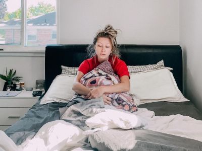 Nikkole Ledda looks sad as she is sitting on her bed.
